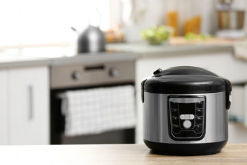 Modern electric multi cooker on table in kitchen. Space for text