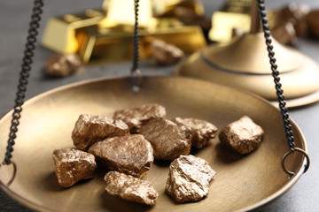 Scale pan with gold lumps on grey table, closeup