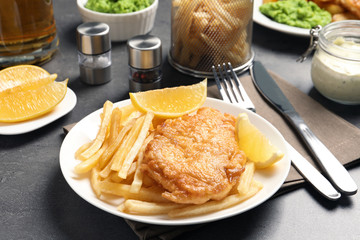 Plate with British traditional fish and potato chips on grey table