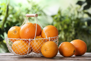 Basket and fresh oranges on wooden table. Space for text