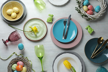 Festive Easter table setting with painted eggs on wooden background, top view