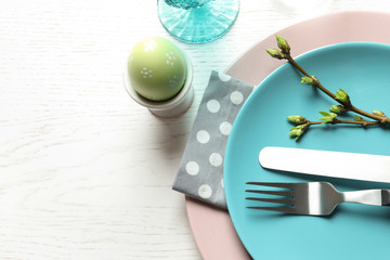 Festive Easter table setting with painted egg on wooden background, top view. Space for text