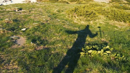 Shadow of a high person raising a gimbal over a green lawn in slow motion