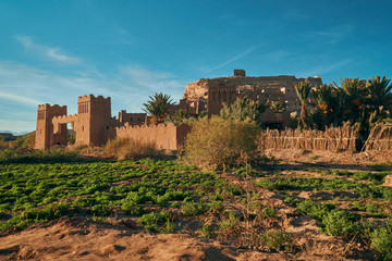 Fototapeta na wymiar Entrance gate with green field near historic unesco heritage ksar of Ait Ben Haddou in Morocco Africa with stones in the foreground