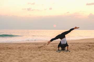 Fototapeta na wymiar Girl doing yoga on the beach, sunset