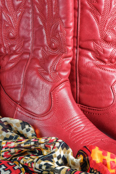 close up on a pair of red cowboy style cowgirl western boots with a southwest pattern scarf