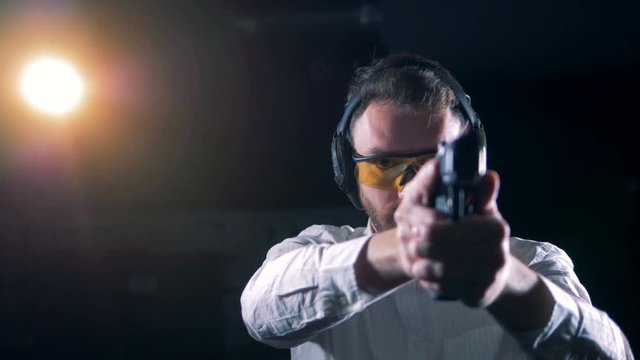 A shooter aims with a pistol at a shooting range, close up.