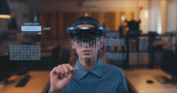 Young adult female using holographic augmented reality glasses in trendy office. Future concept. Generic big data interface added 