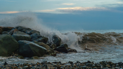 Sea surf on rocks at coastline. Stormy weather. Gloomy sky. Bad weather.