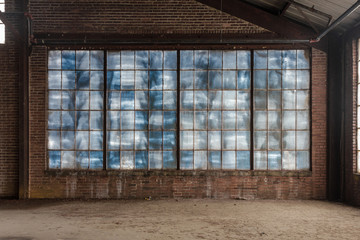 Large blue frosted windows in a loft like space of an abandoned factory with brick walls