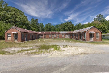 Abandoned redbrick vintage motel with trees and blue skies