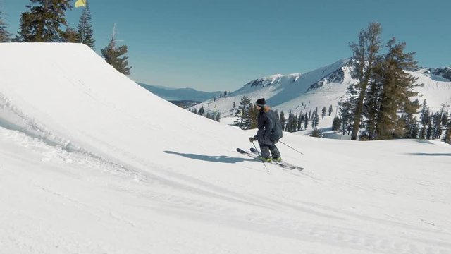 EXTREME ACTION Skier hits huge jump and throws cool trick. Blonde skier races into jump extreme trick in sunny mountains action. Big mountain groomed terrain park at California ski resort