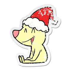 sitting bear distressed sticker cartoon of a wearing santa hat