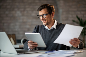 Happy businessman multi-tasking while working on new project in the office.