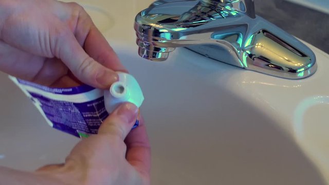 Female hands squeezing an empty toothpaste tube.