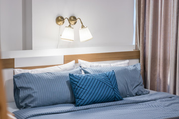 Close-up of bed with blue bedding and lamp