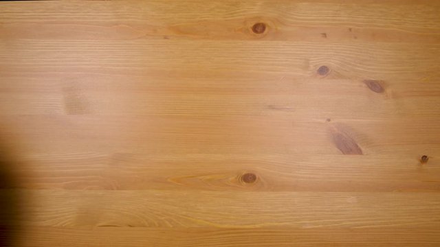 Female hand reaches in and removes plate of curry powder from wood table in 4k top down view with wooden table background.