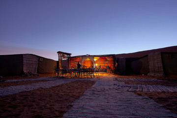 Beautiful evening in a camp with carpets on the sand inside the Sahara desert in Morocco Africa