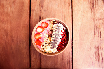 Berries smoothie bowl with strawberry and banana and godi ceed on wooden table.