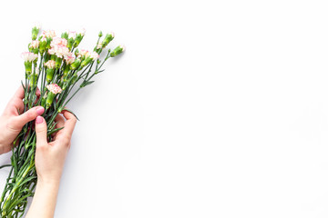 Bouquet of pink carnation in female hands on white background top view copy space