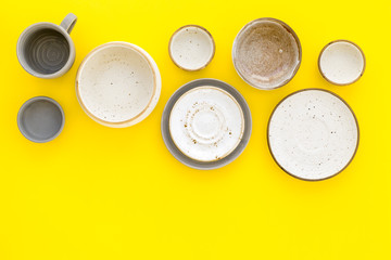 Ceramic tableware pattern. Empty plates and mugs on yellow background top view copy space