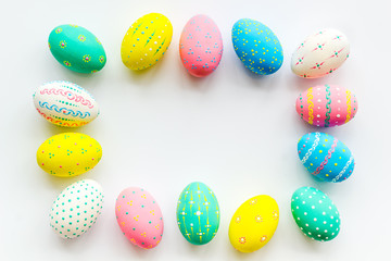 Colorful Easter eggs frame on white background top view copy space