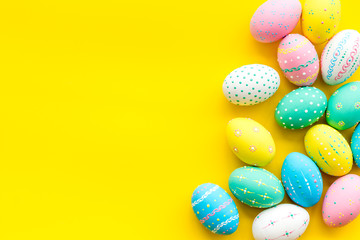 Easter composition. Decorated pastel Easter eggs on yellow background copy space border