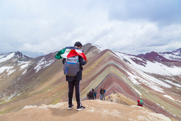 RAINBOW Mountain PERU-20. Dezember 2018, Mann mit mexikanischer Flagge mit Panoramablick, Vinicunca, Touristen und Einheimische, Seven Colors Mountain, Seven Colors Mountain, Trekking, Cusco, Perú.