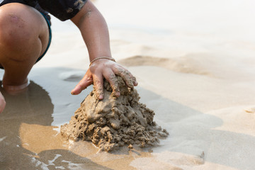 Close up Asian children sitting playing sand in Holiday at the sea Thailand.