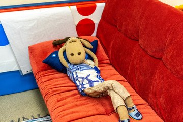 .Lying on the couch deer in clothes, and thinking deep thought. A toy for children, bright colors....