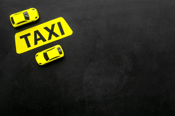 Taxi concept. Yellow service sign text taxi near car toy on black background top view copy space
