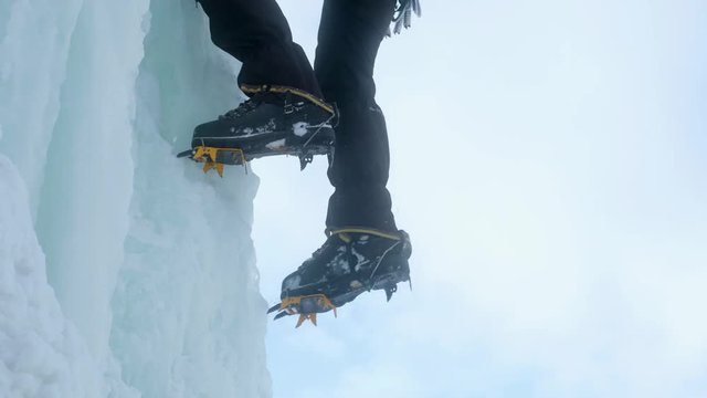 Crampons close-up on his feet ice climber, climber on a frozen waterfall.