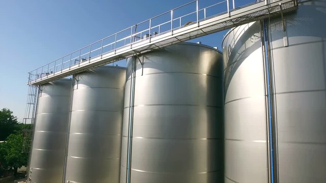 Large stainless steel wine distilling tanks. Silos for wine and beer fermentation . Steel barrels for fermentation of wine in winemaker factory . Dolly , ronin movement a long row of wine vats . 