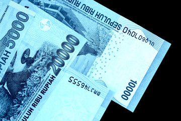 Several Indonesian rupiah banknotes close up. Blue color toned