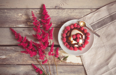 Red astilbe flowers and homemade italian dessert panna cotta with fresh raspberry and chocolate...