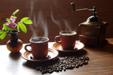 Two cups of hot coffee, from which comes steam.