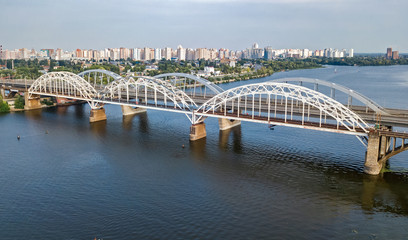 Aerial top view of automobile and railroad Darnitsky bridge across Dnieper river from above, Kiev (Kyiv) city skyline, Ukraine
