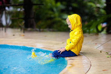 Kid in swimming pool in rain. Tropical storm.