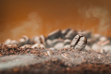 Close up Coffee beans over the cofee powder with smoke