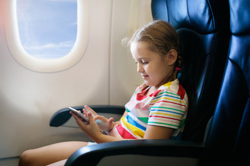 Fototapeta na wymiar Child in airplane. Fly with family. Kids travel.pl