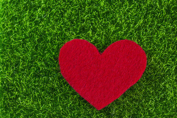 Red felt heart on green background