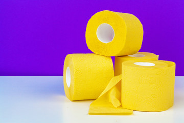 Minimalistic composition of bright yellow toilet paper rolls on purple background