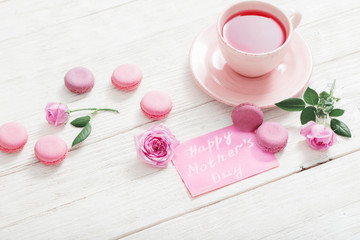 cup of tea and pink macaroons on white wooden table