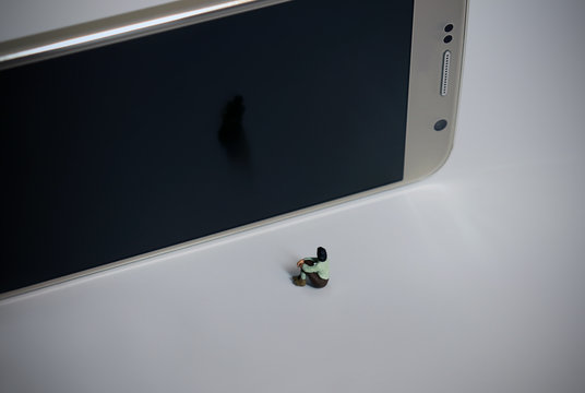 A sitting miniature woman and a Smart phone.