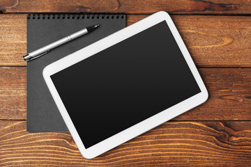 Tablet with notepad on wooden background