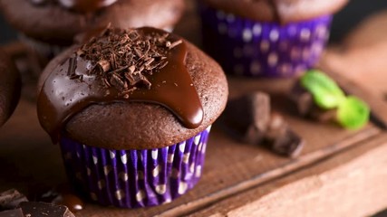 Chocolate muffins or cupcakes with chocolate glaze, ganache and sprinkles on wooden serving board - Powered by Adobe