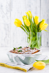 Apple pie in dishes on a white background and a bouquet of spring yellow tulips. Homemade pastries with fruit for a delicious breakfast Easter breakfast. Free space for text. Copy space