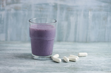 Glass of Protein Shake with milk and blueberries and BCAA amino acids in background. Sport nutrition. Rustic wooden background. Copy space. 