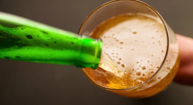 Beer is pouring and foaming in Glass from bottle Top View closeup Slow motion video