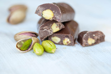 Eastern Turkish sweets with pistachios on a white wooden background. Chocolate candy with pistachios and pistachio nuts around.